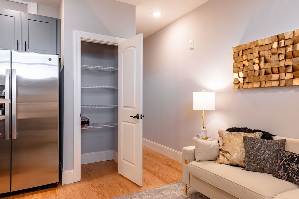 A modern kitchen with a refrigerator, a couch, and a wooden wall art.