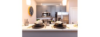 A kitchen with a white countertop and a clock on the wall.
