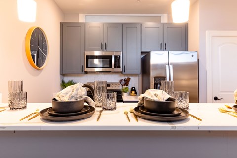 A kitchen with a white countertop and a clock on the wall.