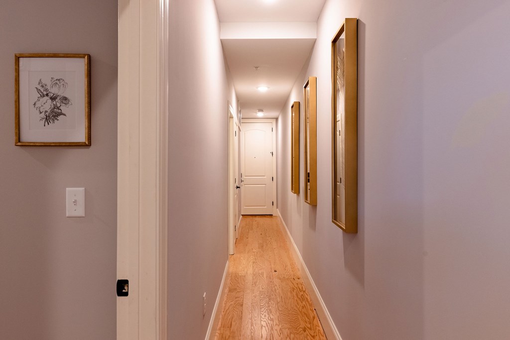 A hallway with a light on the wall and pictures on the wall.