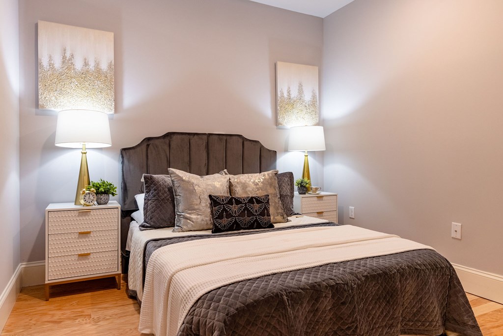 A bedroom with two beds, nightstands, and lamps.