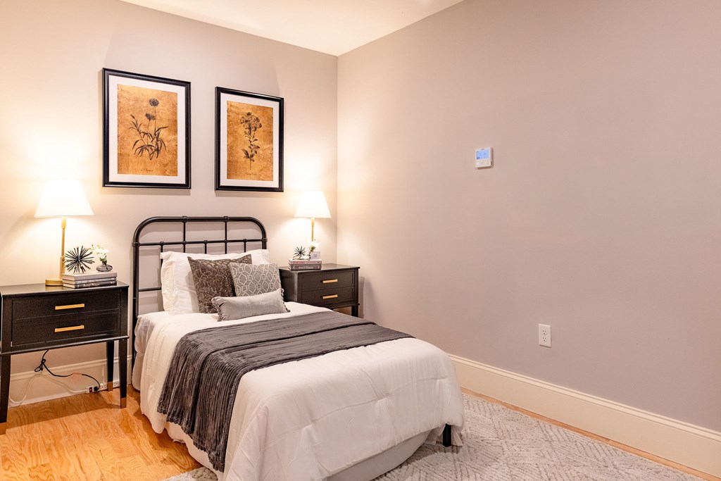 A bedroom with a bed, nightstands, and two wall lamps.