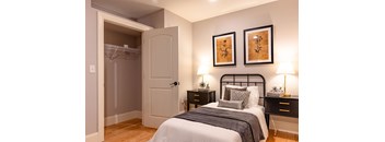 A bedroom with a bed, nightstands, and two wall-mounted lamps.