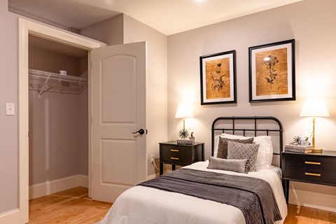 A bedroom with a bed, nightstands, and two wall-mounted lamps.