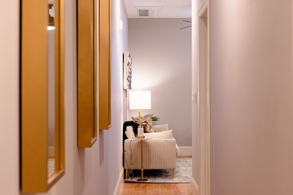A hallway with a light on and a chair in the middle.
