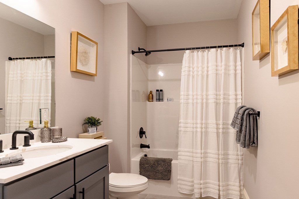 A bathroom with a white shower curtain and a white toilet.