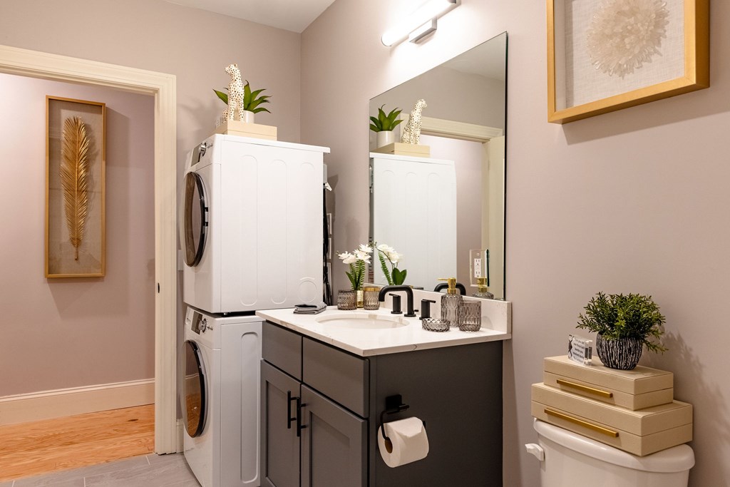 A bathroom with a washing machine and a mirror.