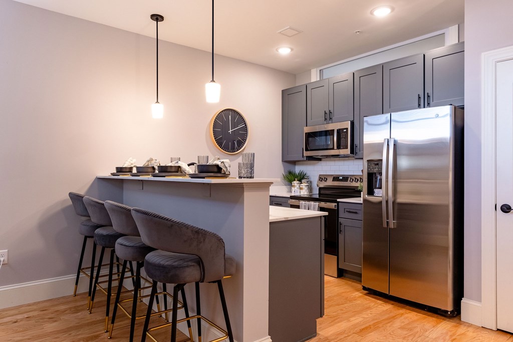 A kitchen with a bar area and a clock on the wall.