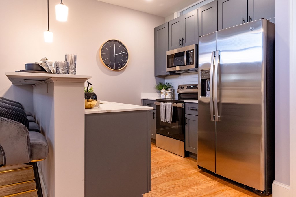 A modern kitchen with a stainless steel refrigerator and wooden floors.