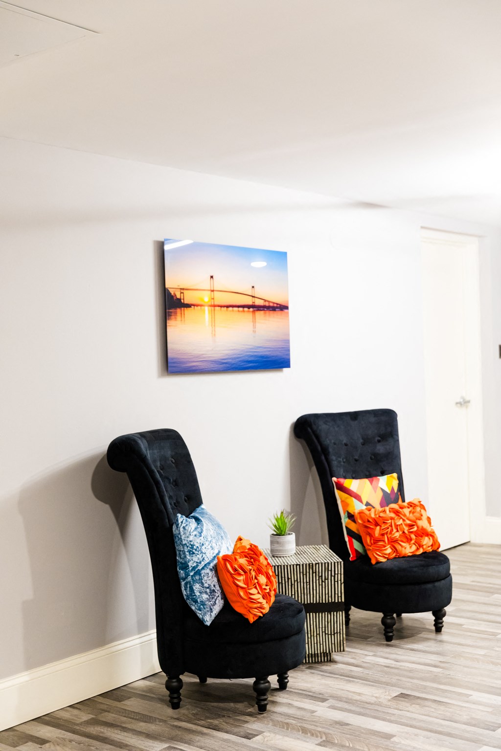 two black chairs in a room with a painting on the wall