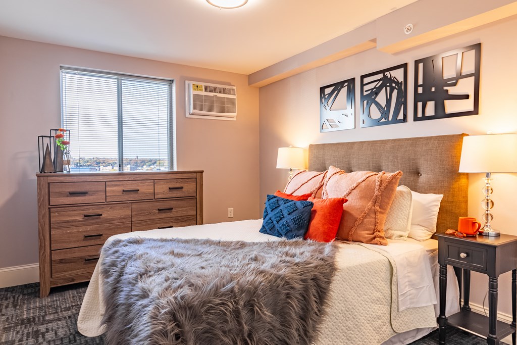 a bedroom with a bed and a dresser and a window