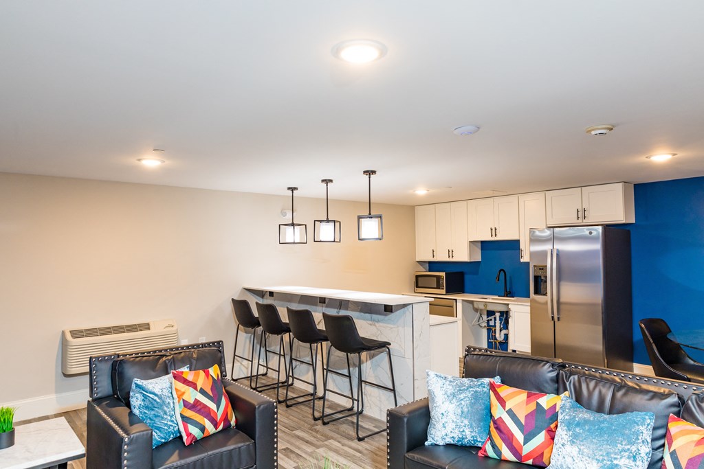 a living room with a kitchen with a bar and couches