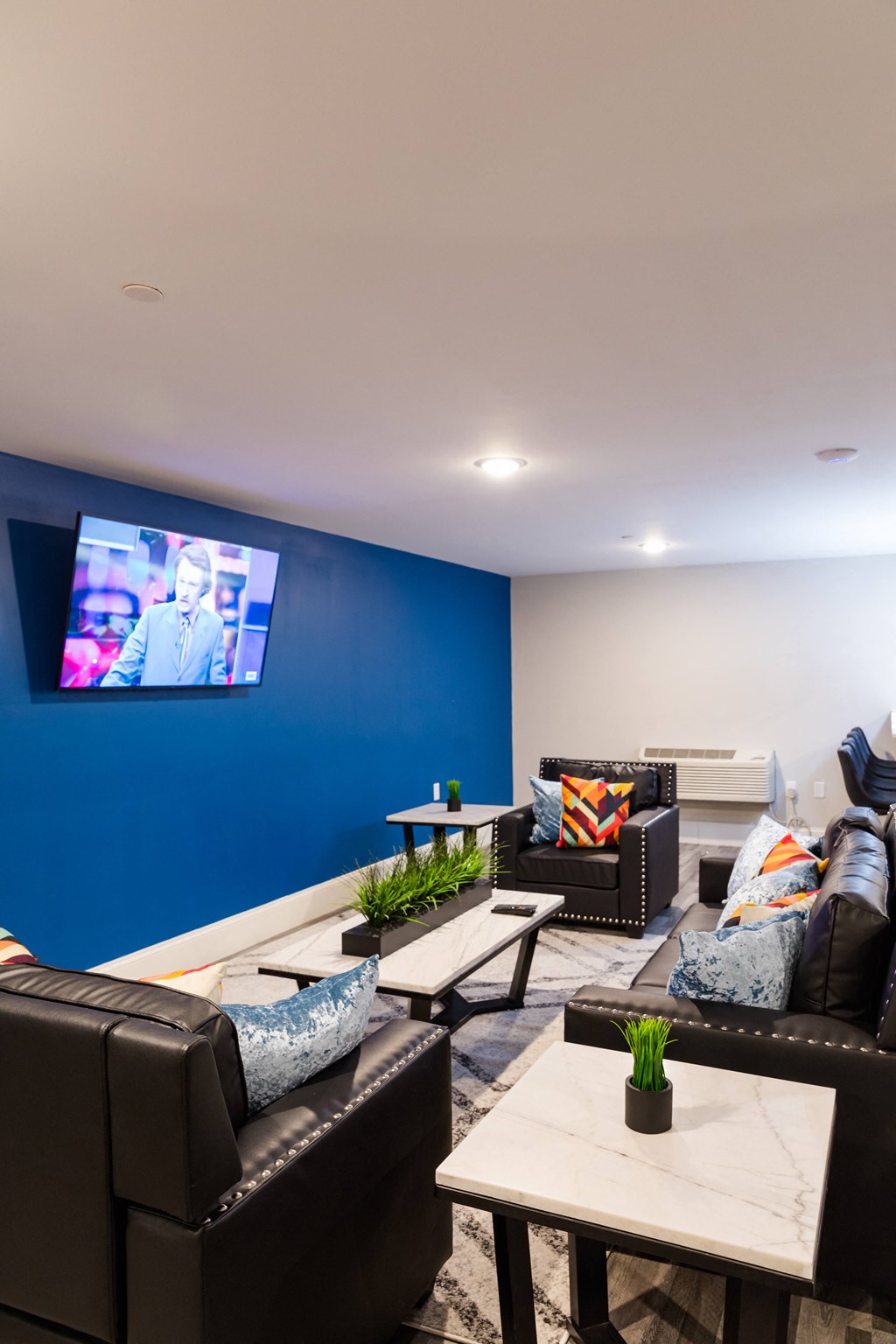 a living room with couches and tables and a tv on the wall