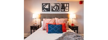 a bedroom with a bed with colorful pillows and artwork on the wall above it