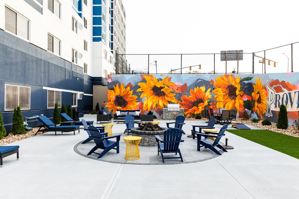 a patio with blue chairs and yellow tables and a mural of sunflowers