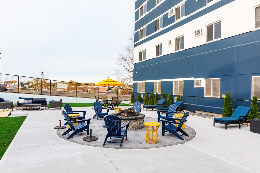 an outdoor patio with chairs and a fire pit next to a building