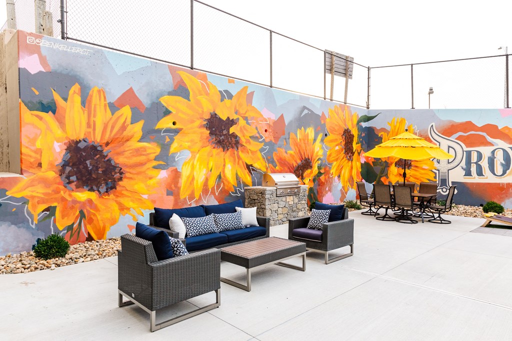 a patio with seating and a mural of sunflowers