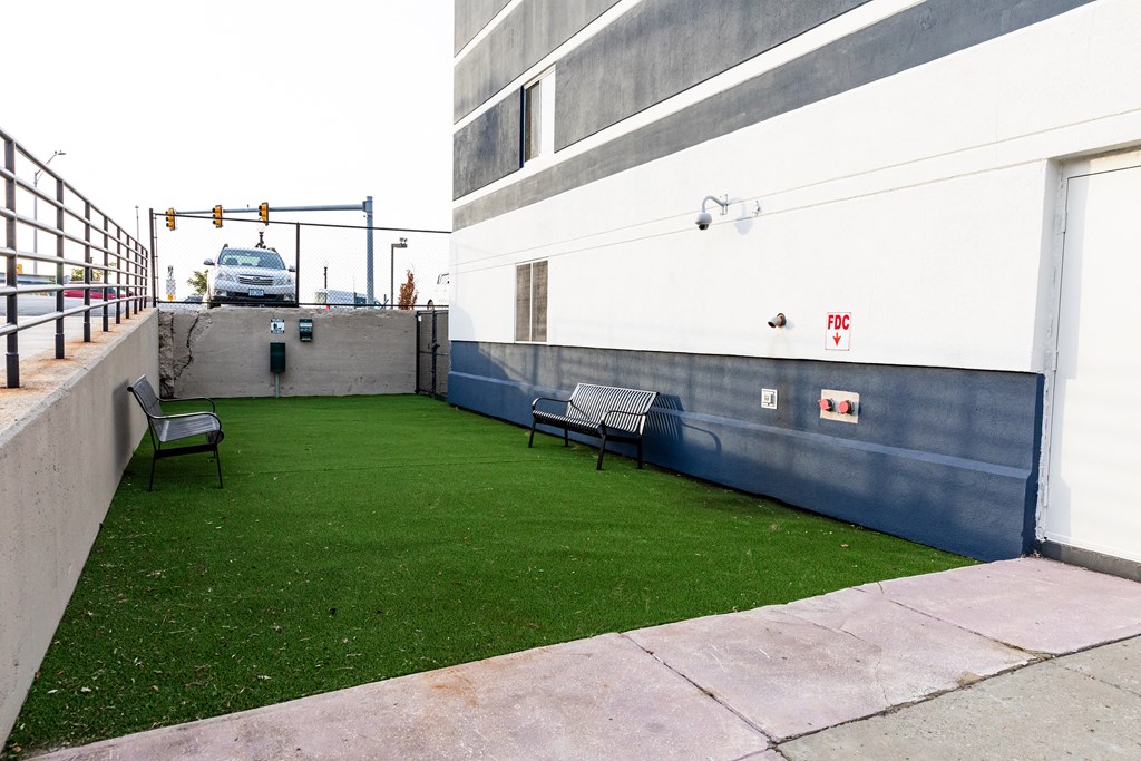 a yard with green grass and benches next to a building