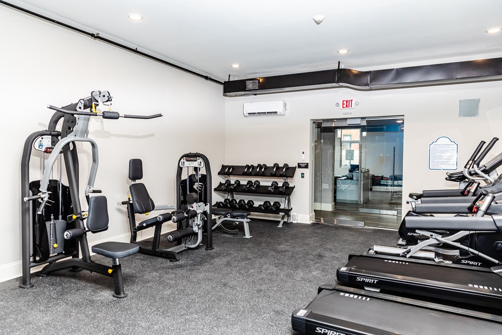 a gym with treadmills and other exercise equipment in a room with a door