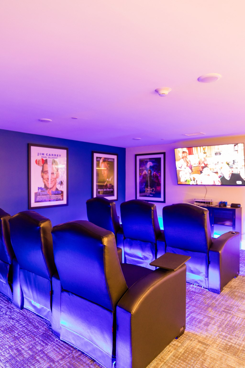 a theater room with blue chairs and a tv
