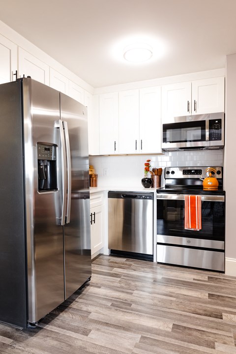 a modern kitchen with stainless steel appliances and white cabinets