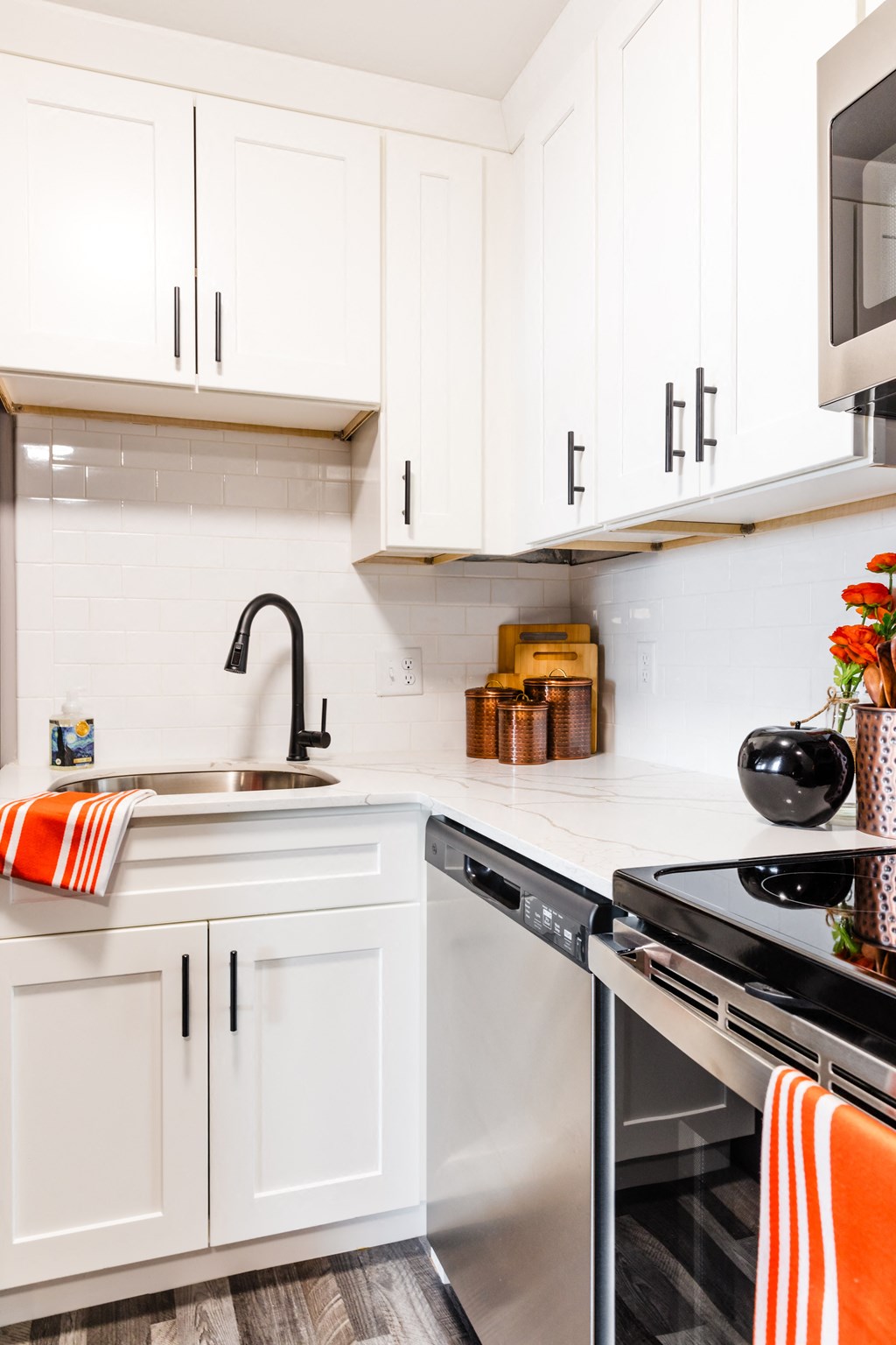 a white kitchen with white cabinets and black appliances and a sink