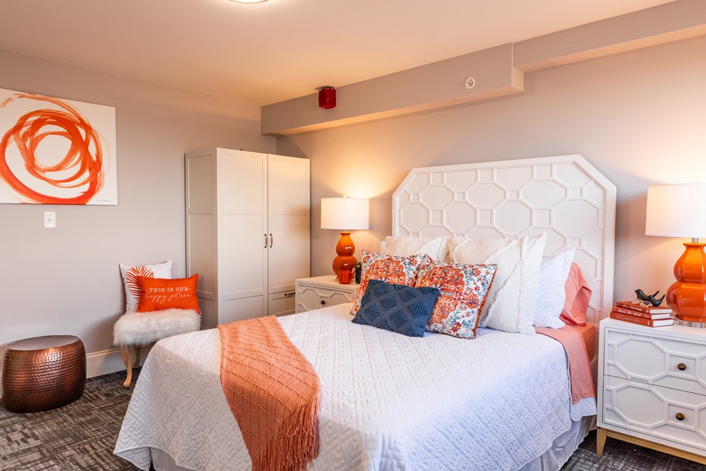 a bedroom with a white bed and orange pillows