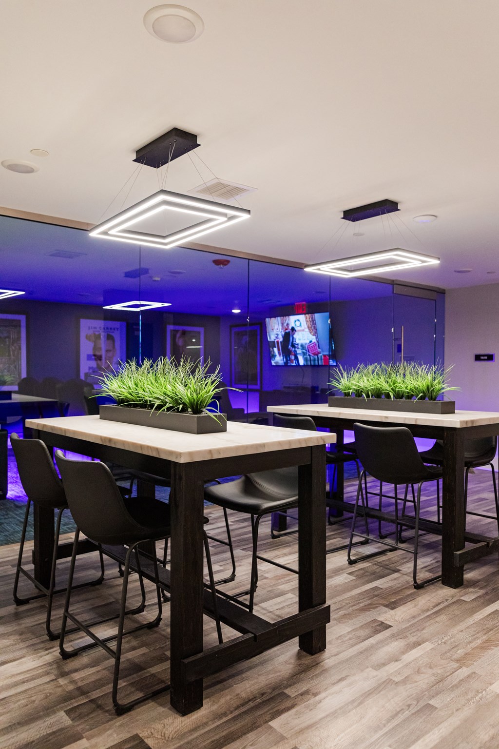a room with tables and chairs and a tv in the background