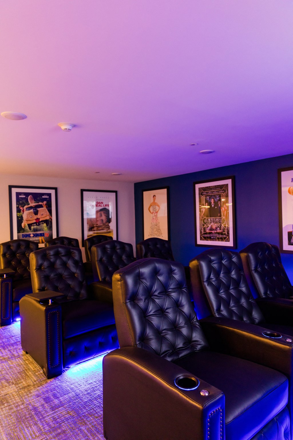 a theater room with blue lighting and leather chairs