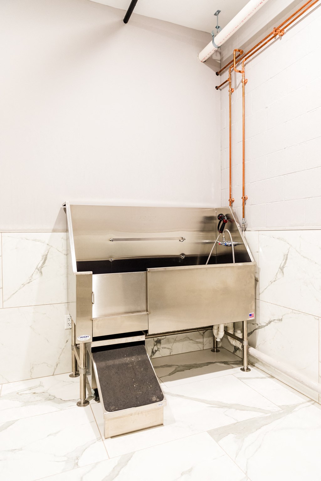 a large stainless steel sink in a kitchen with white tiles