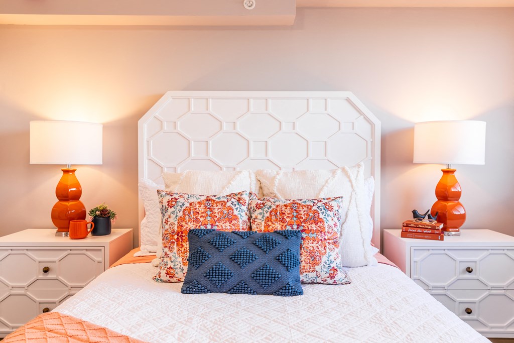 a white bed with pillows and two night stands with lamps