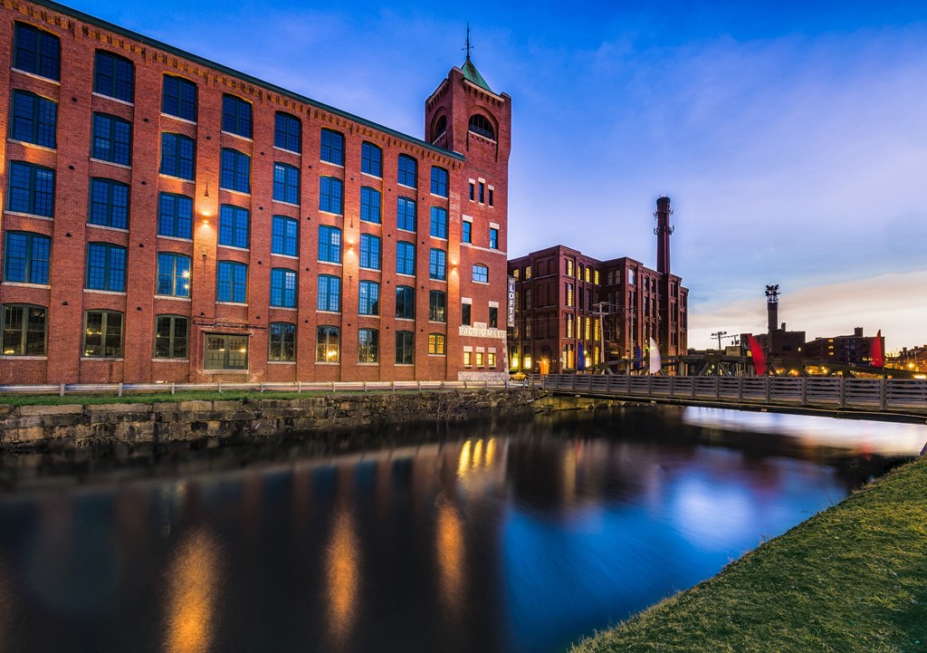 a bridge over a river in front of a large brick building
