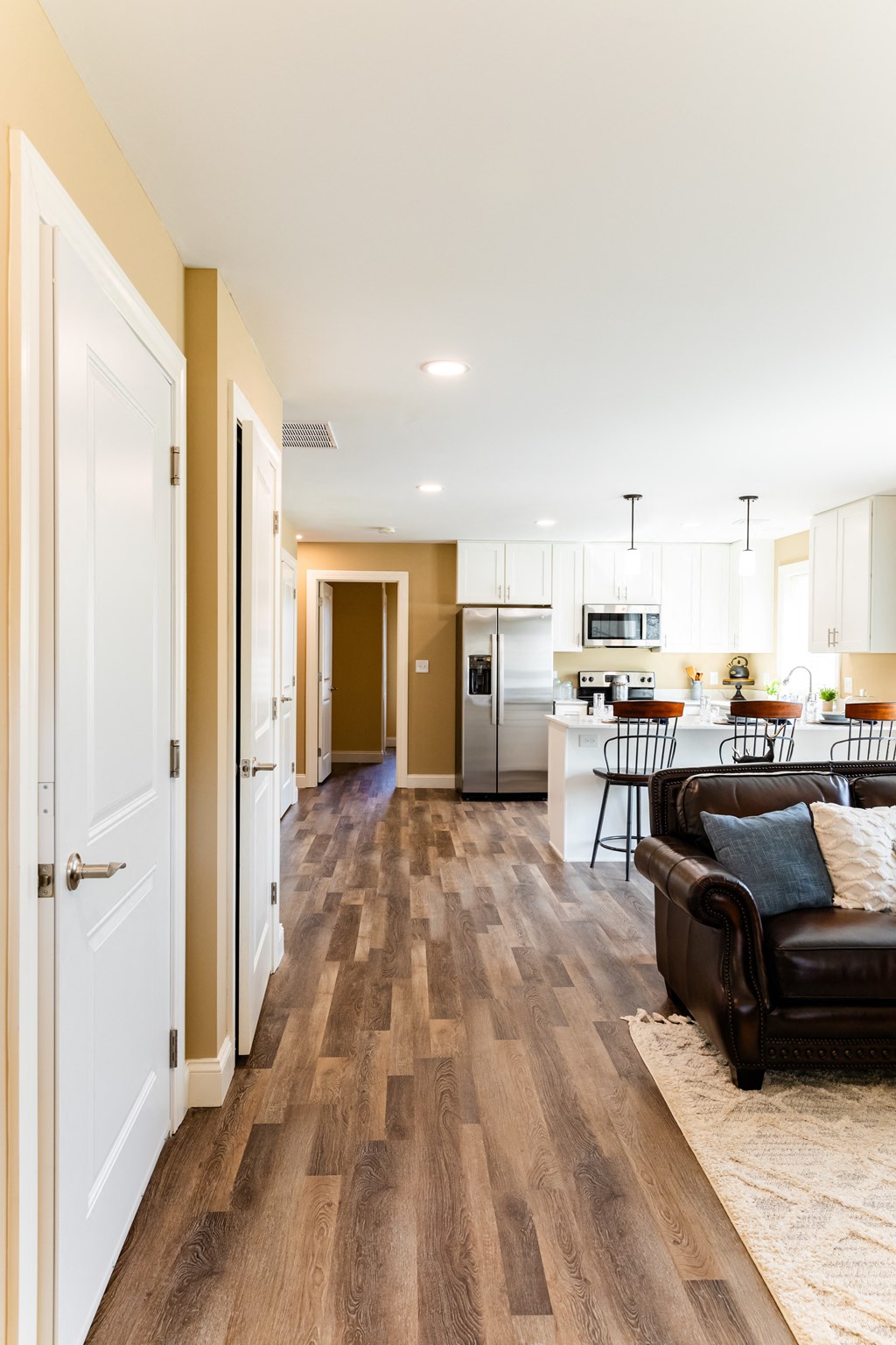 a living room and kitchen with a hard wood floor and white cabinets