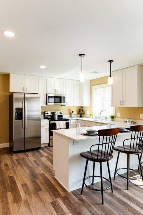 a kitchen with white cabinets and a island with three chairs