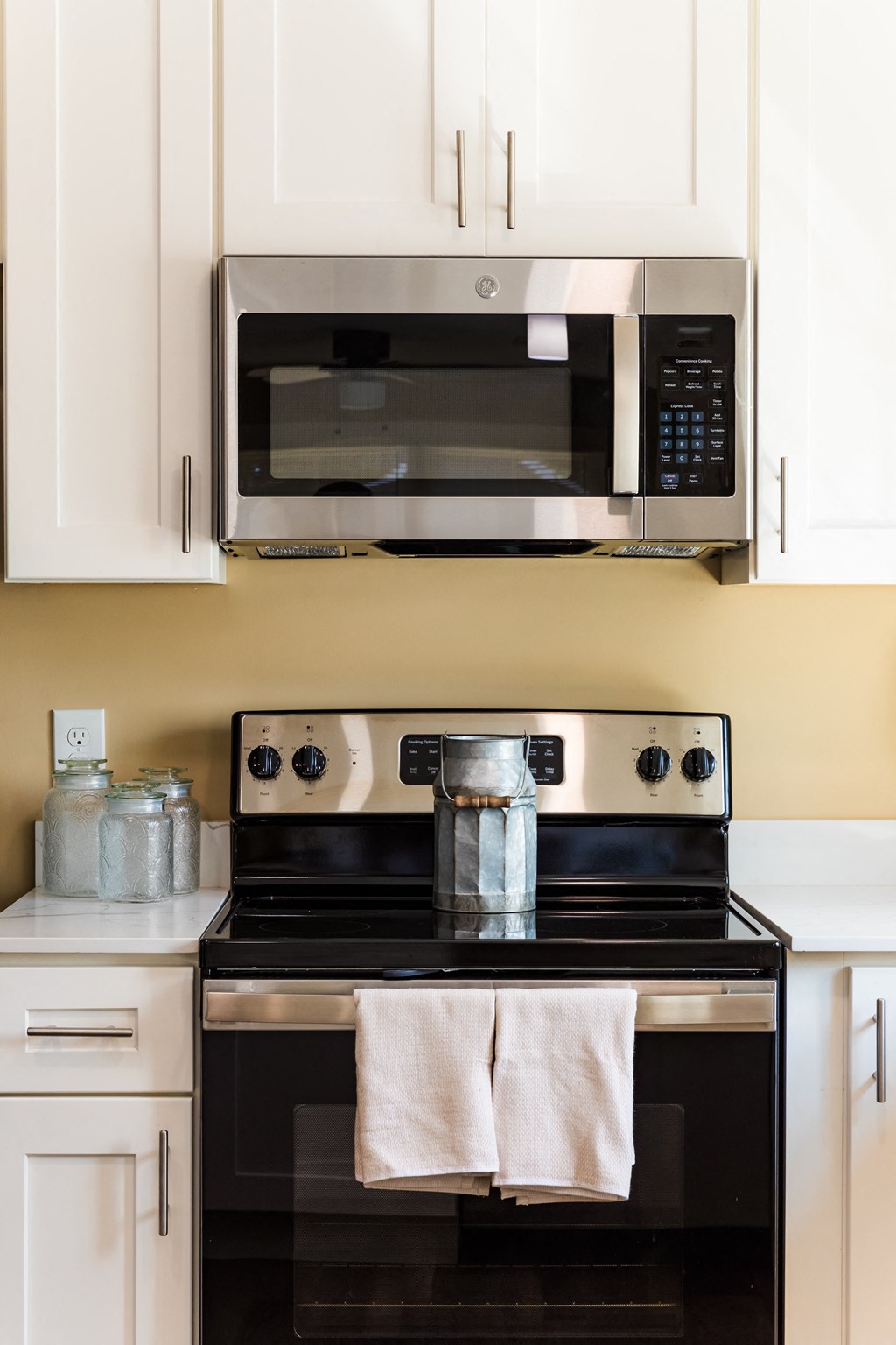 a kitchen with white cabinets and a black stove and a microwave