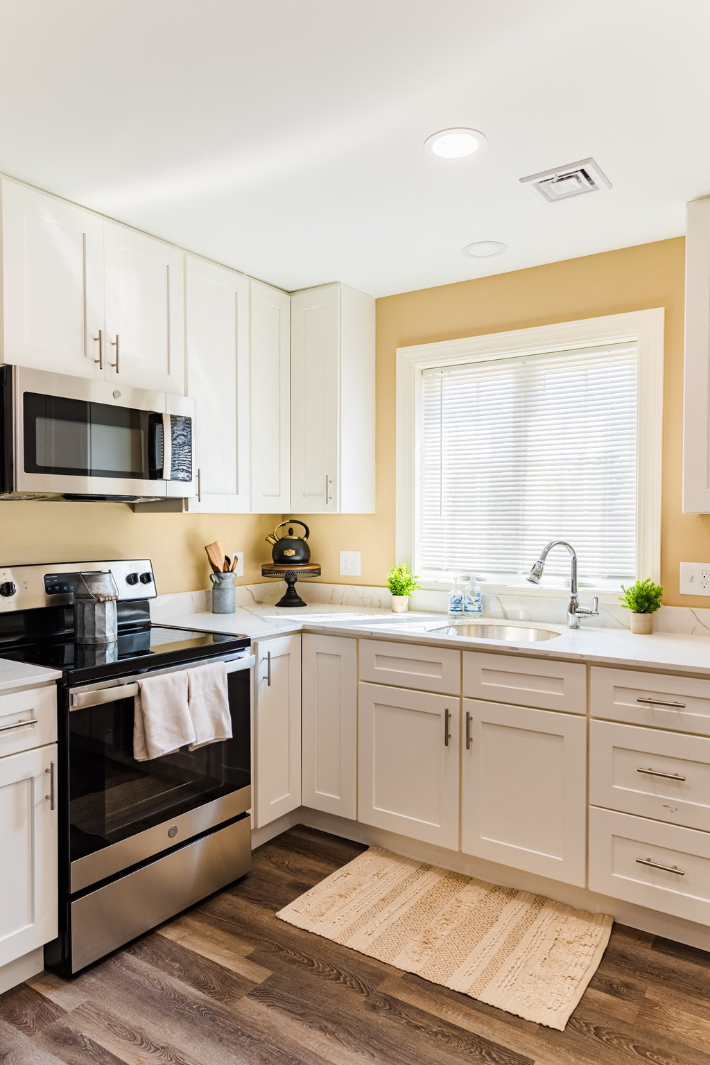a kitchen with white cabinets and black appliances and a window