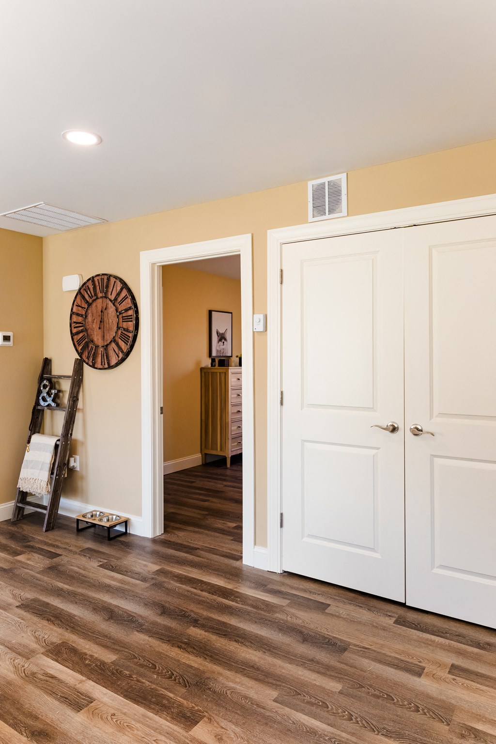 a room with white doors and a hallway with a clock on the wall and a