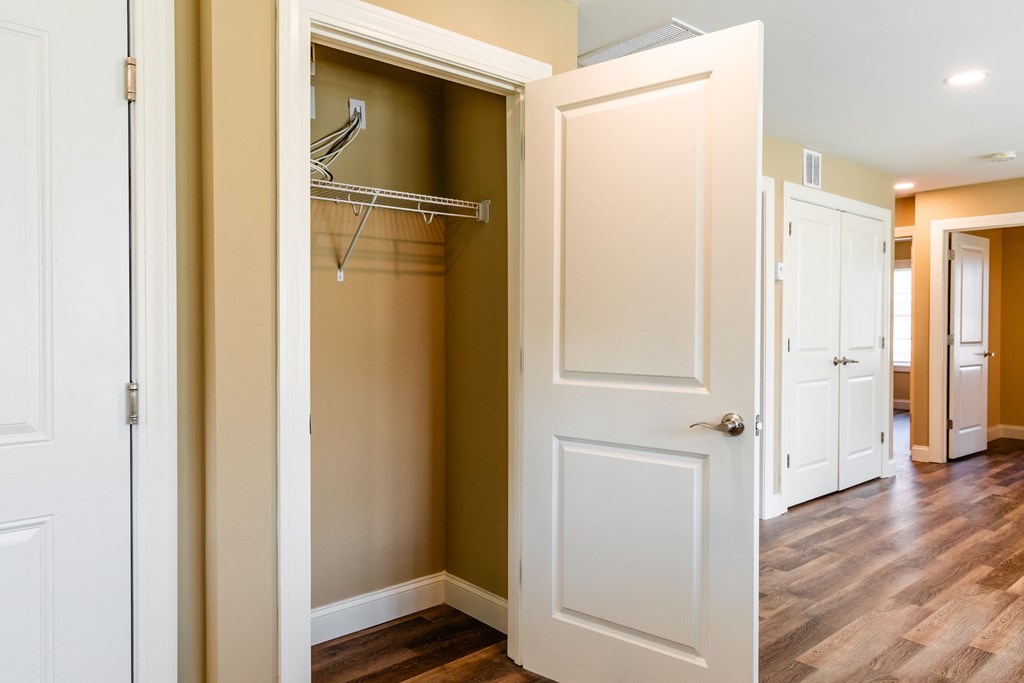 a walk in closet with a white door and a closet hanger