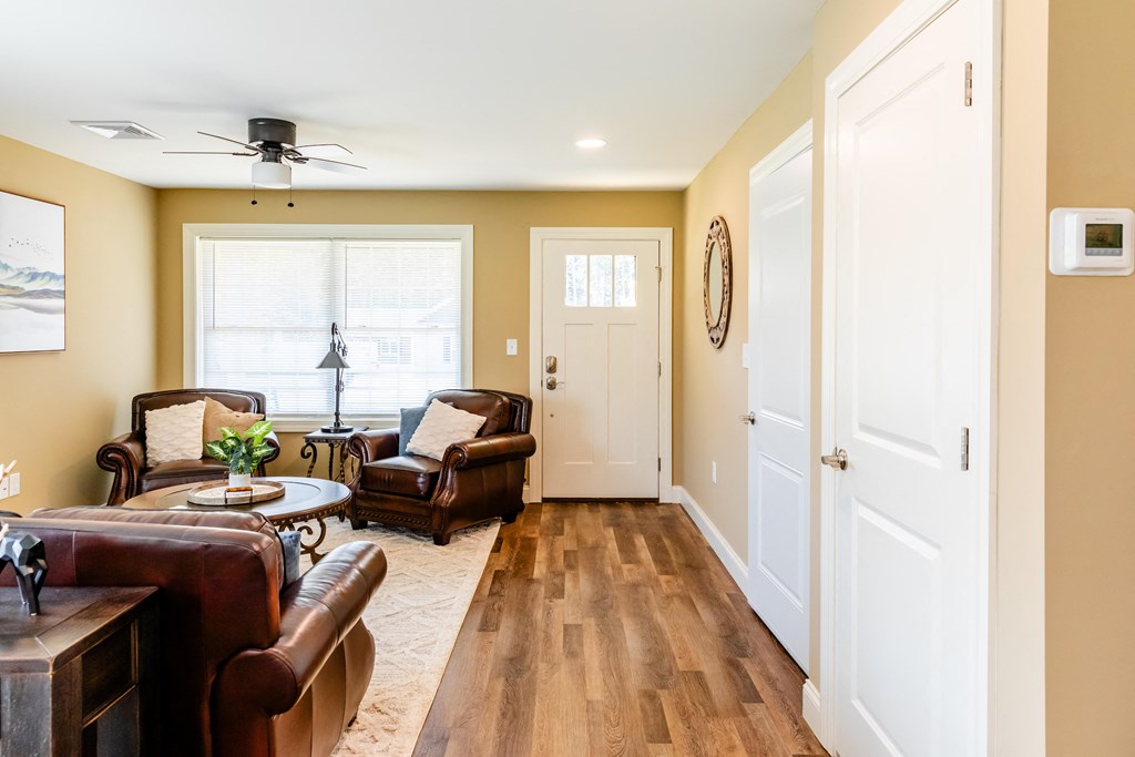 a living room with leather furniture and a ceiling fan