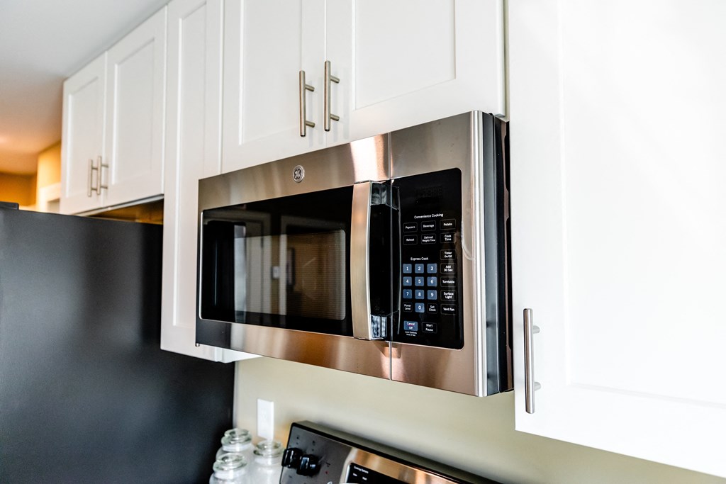 a kitchen with a stainless steel microwave oven and white cabinets