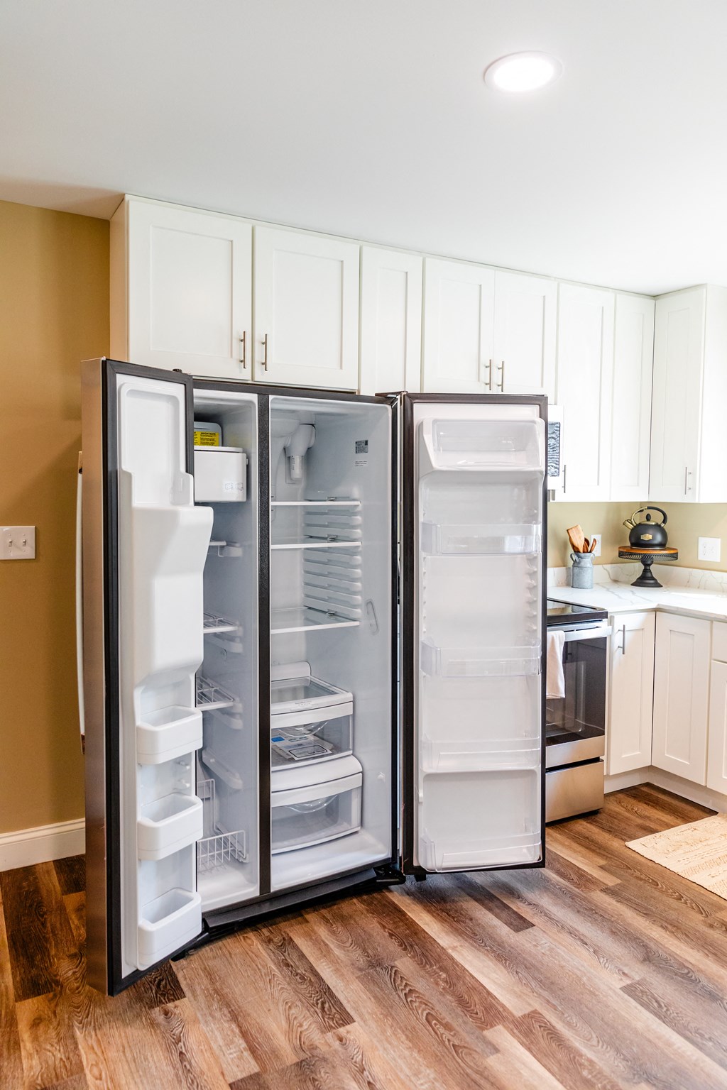 an empty refrigerator in a kitchen with white cabinets