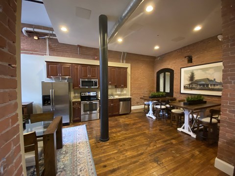 a kitchen and living room with a wood floor and brick walls