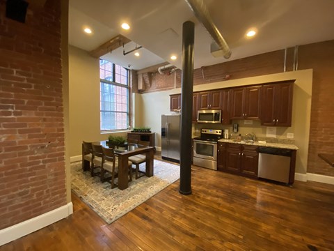 an open kitchen and dining room with a brick wall and wood floors