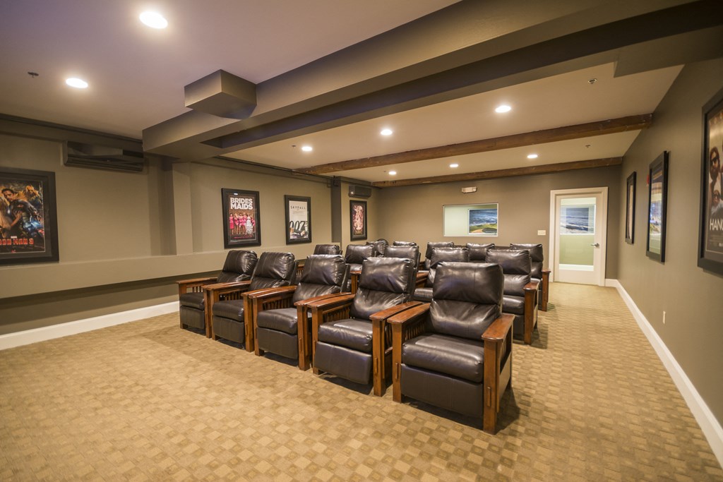 a theater room with leather chairs and a projector screen