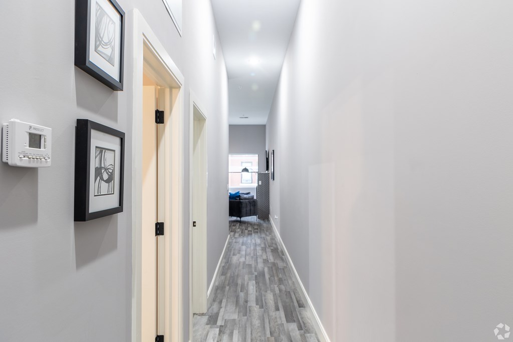 A hallway with a door on the left and a framed picture on the wall.