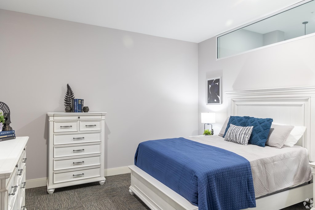 A bedroom with a white bed and a blue blanket.
