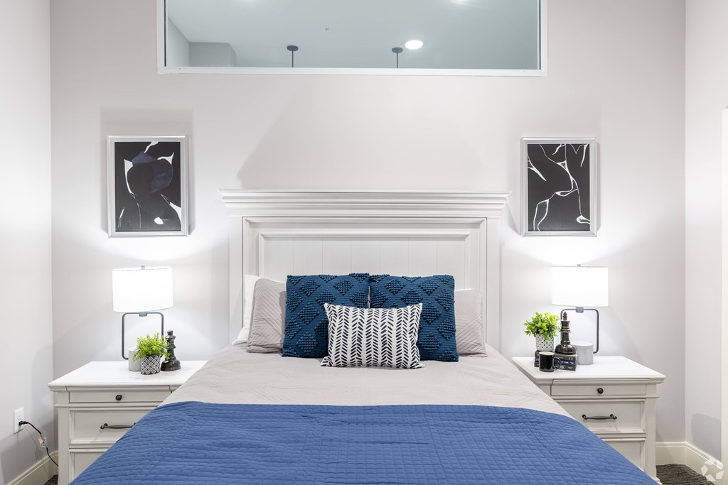 A bedroom with a white bed and blue bedspread.
