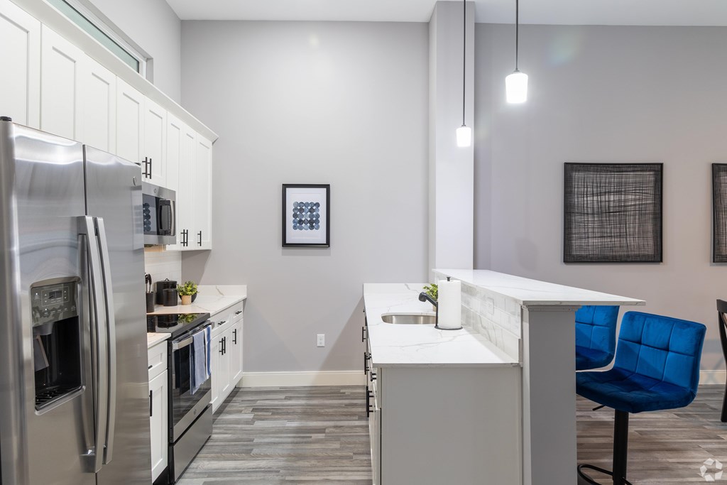 A modern kitchen with a blue chair and stainless steel appliances.