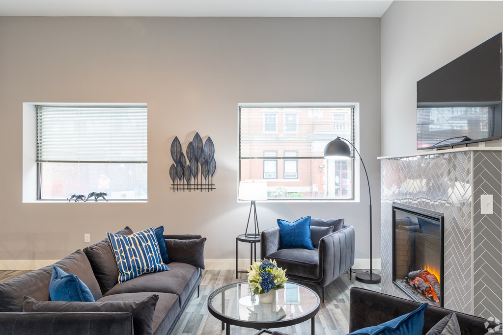 A living room with a grey couch and a fireplace.
