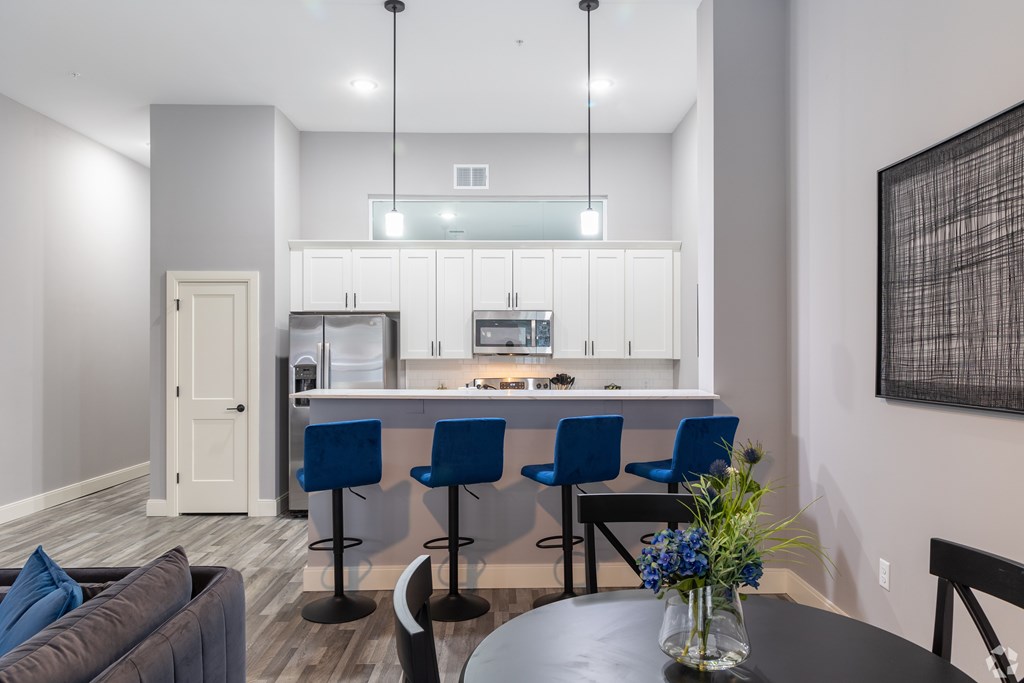 A modern kitchen with blue chairs and a dining table.